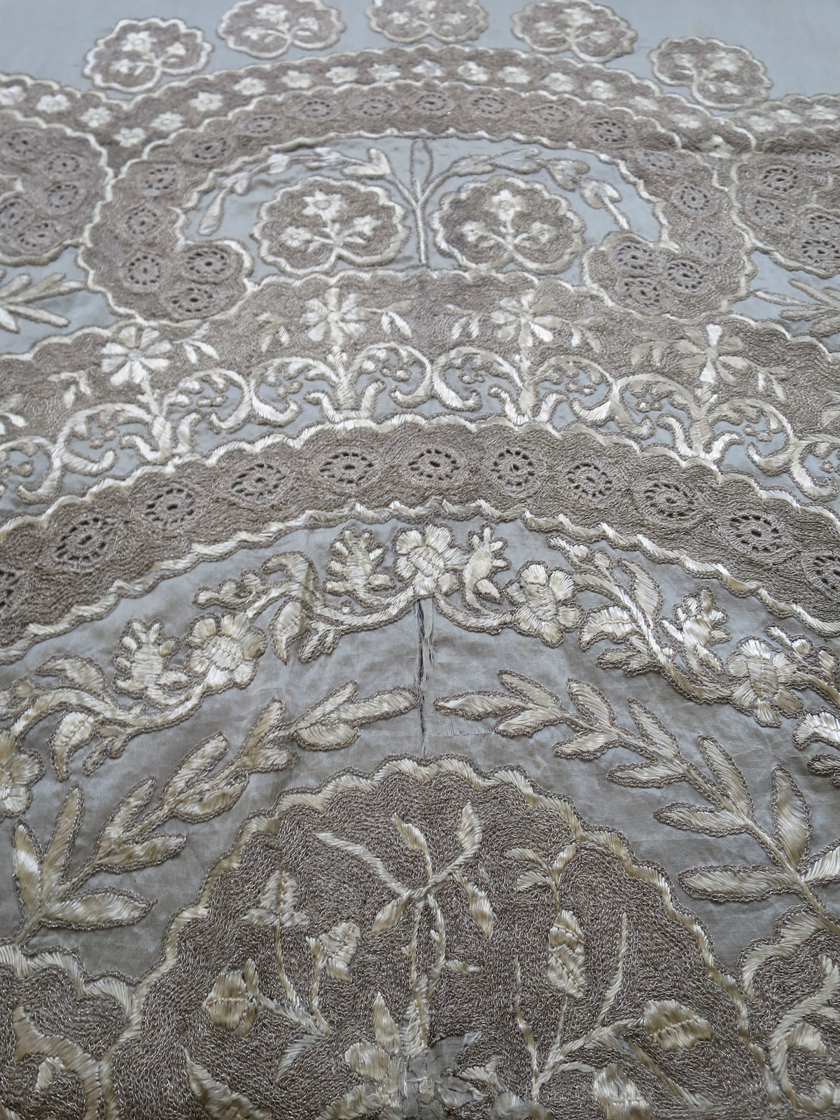 Close up of vertical splitting and shattering on the delicate silk gauze background of a heavy antique Zardozi textile.