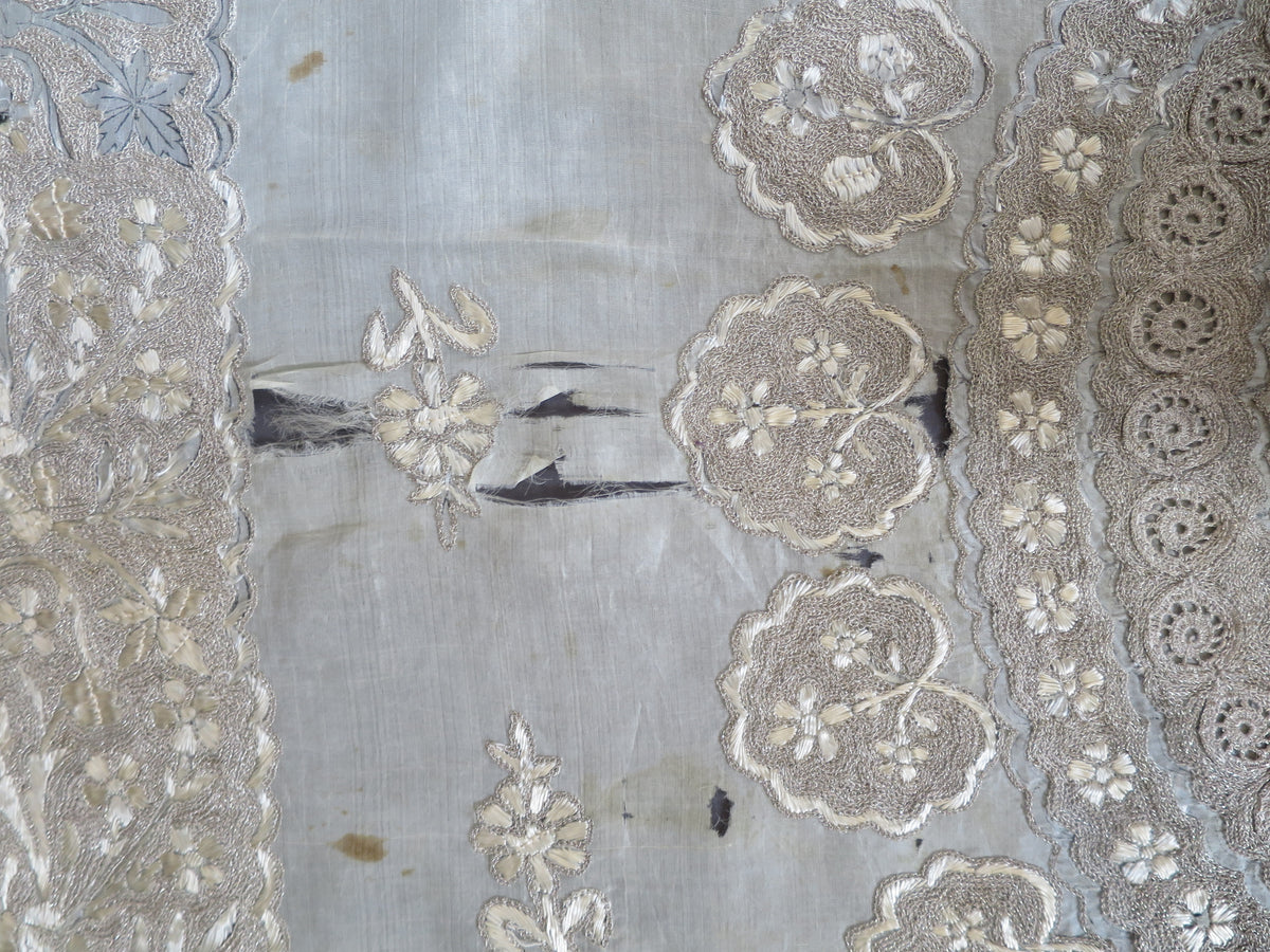 Close up of vertical splitting and shattering on the delicate silk gauze background of a heavy antique Zardozi textile.