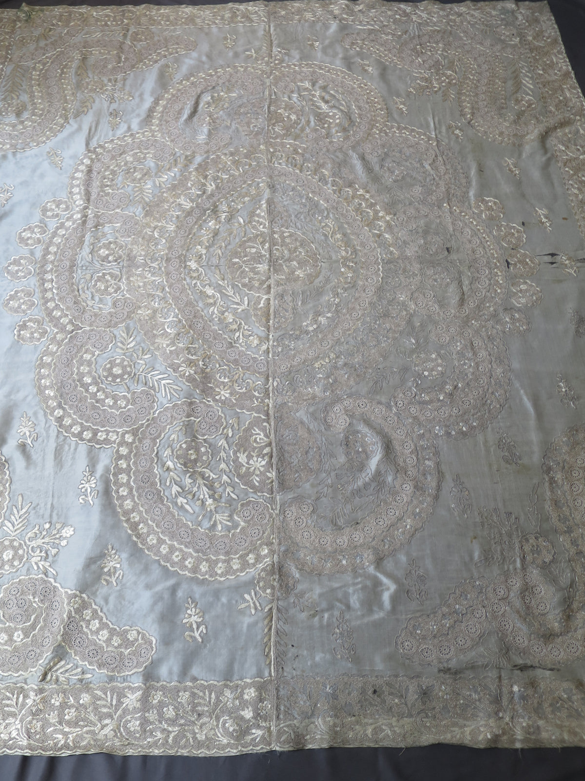 View of coverlet showing foxing to silk embroidery on one side