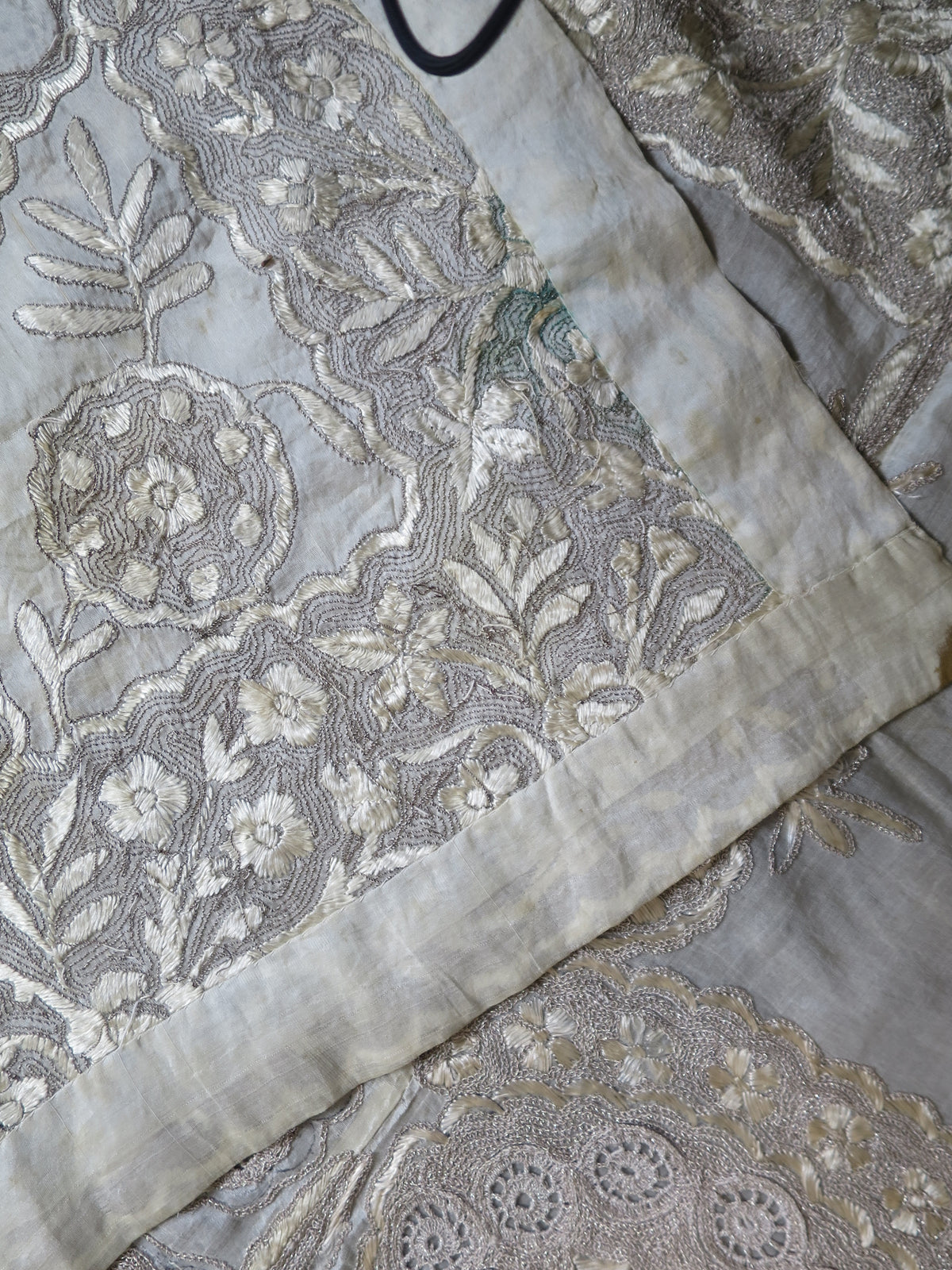 Reverse side of a large antique Indian Zardozi panel showing a plain silk border strip and age-related foxing.
