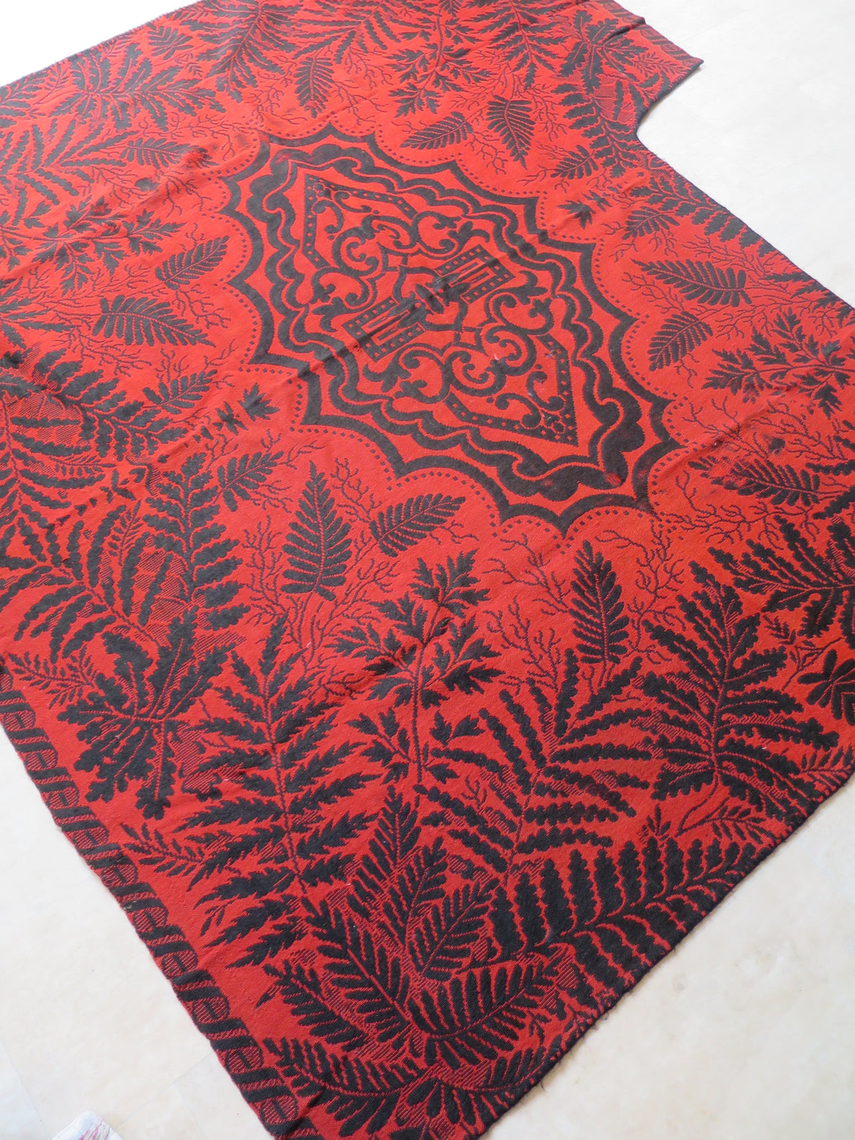 Reversible side of an antique Jacquard coverlet, showing the inverted colorway with a predominantly madder-red background and dark indigo pattern.