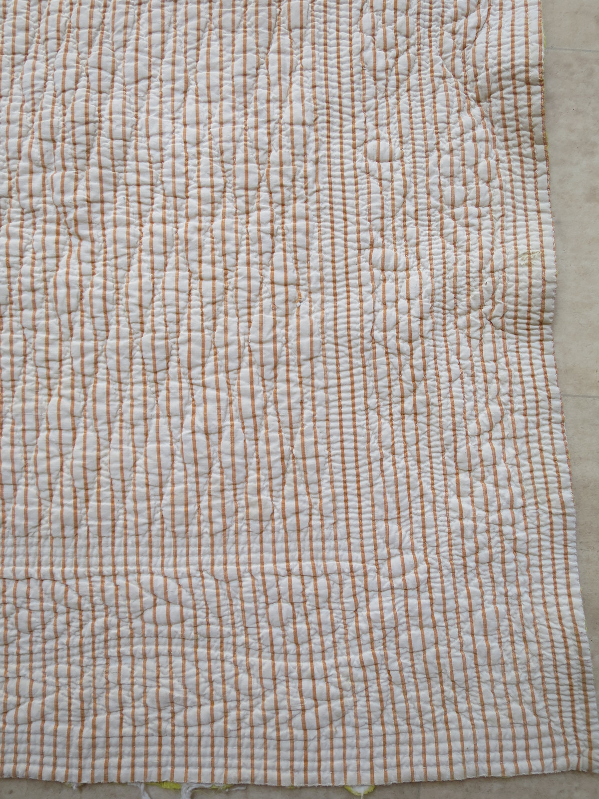 Quilting detail on the ochre pencil-stripe reverse