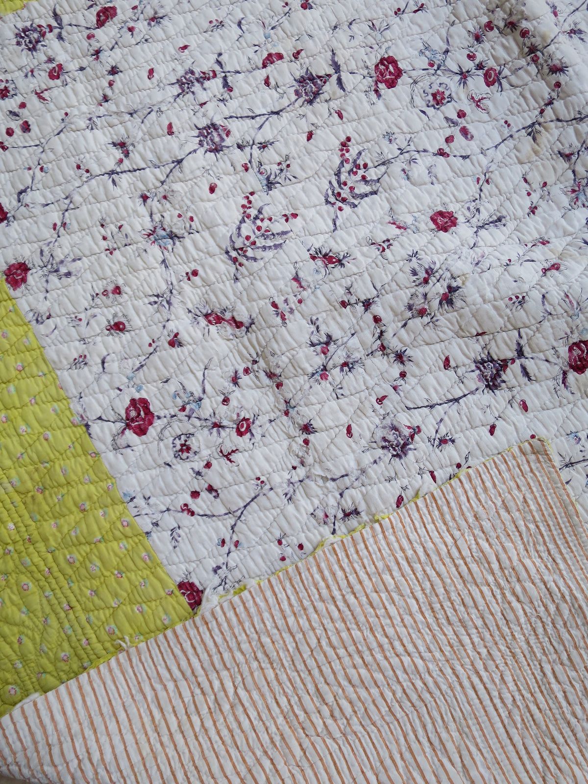 Front of the quilt showing the centre print and yellow border, folded back to reveal a strip of the reverse