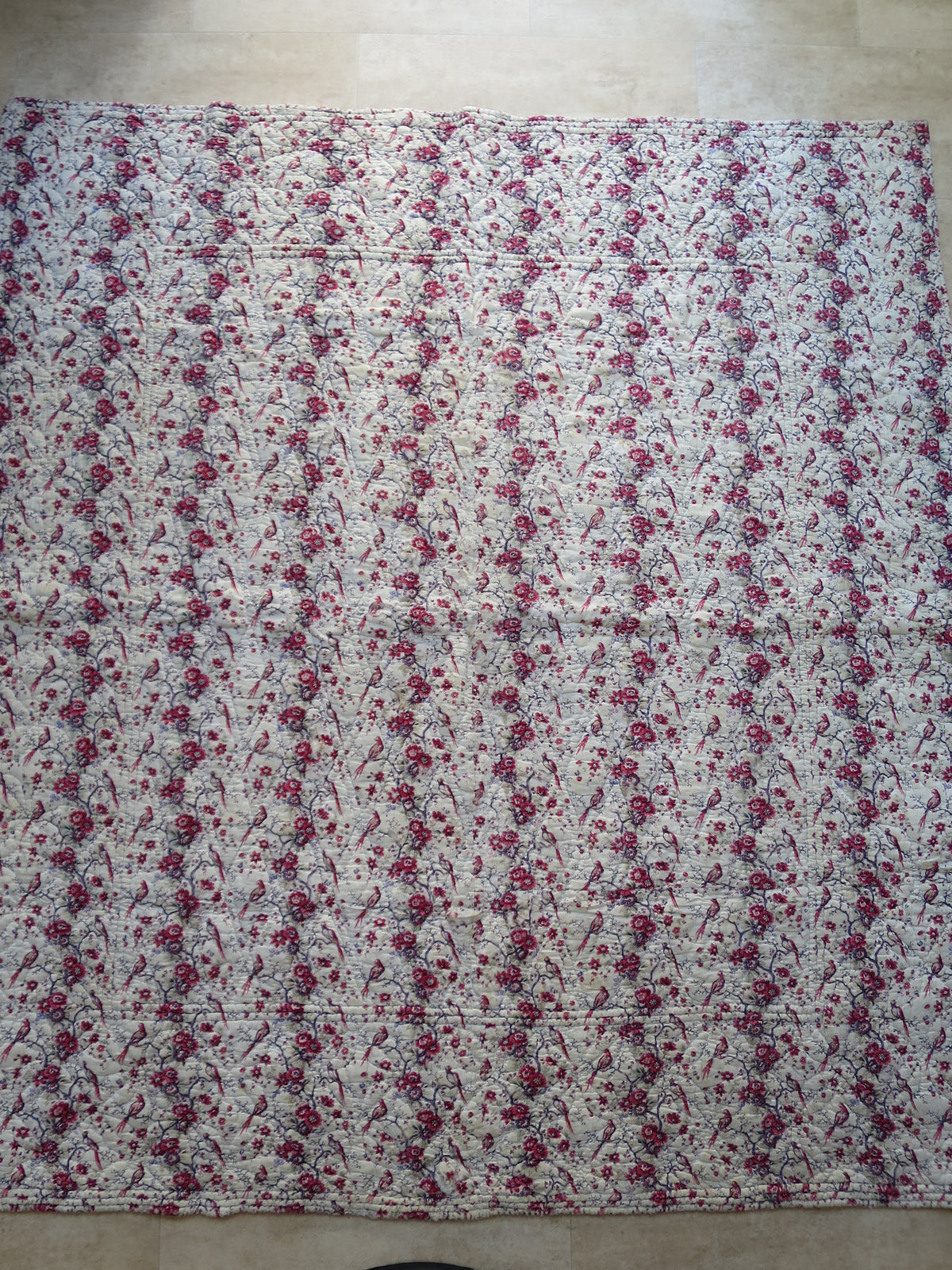 French piqué quilt with a block-printed front showing long-tailed birds among floral trails.
