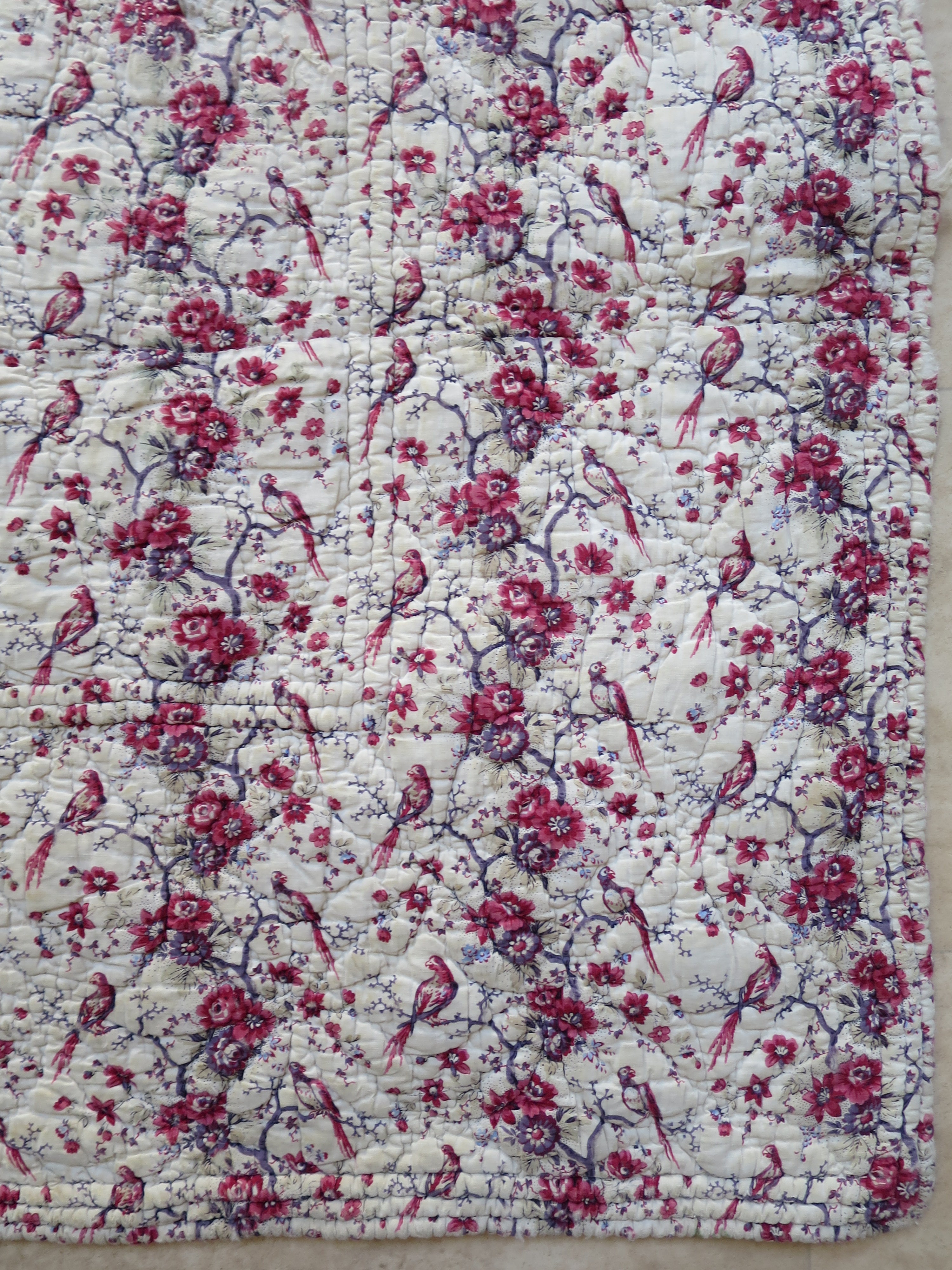 Repeating bird and floral pattern on the block-printed front of the French quilt.