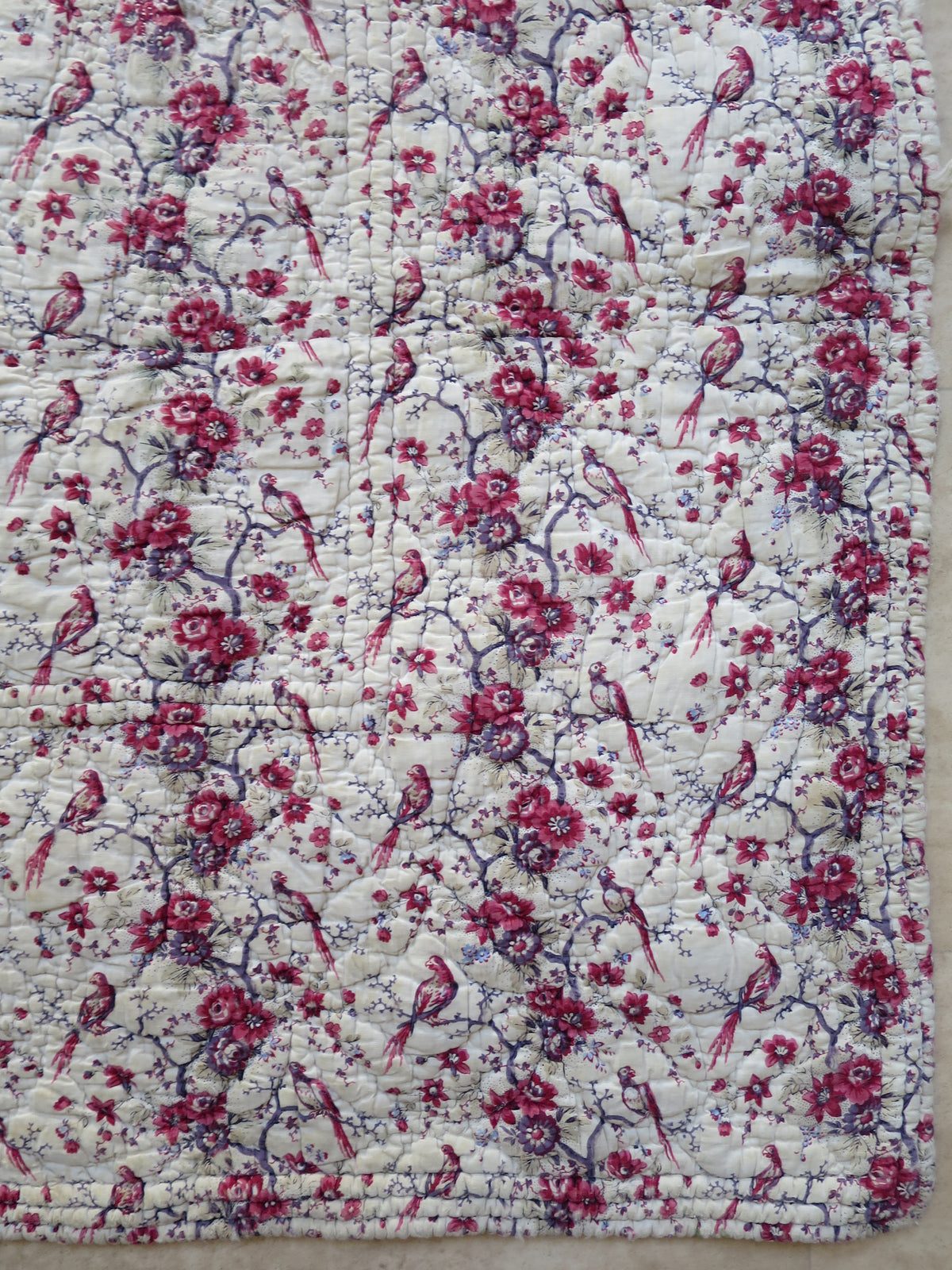 Repeating bird and floral pattern on the block-printed front of the French quilt.