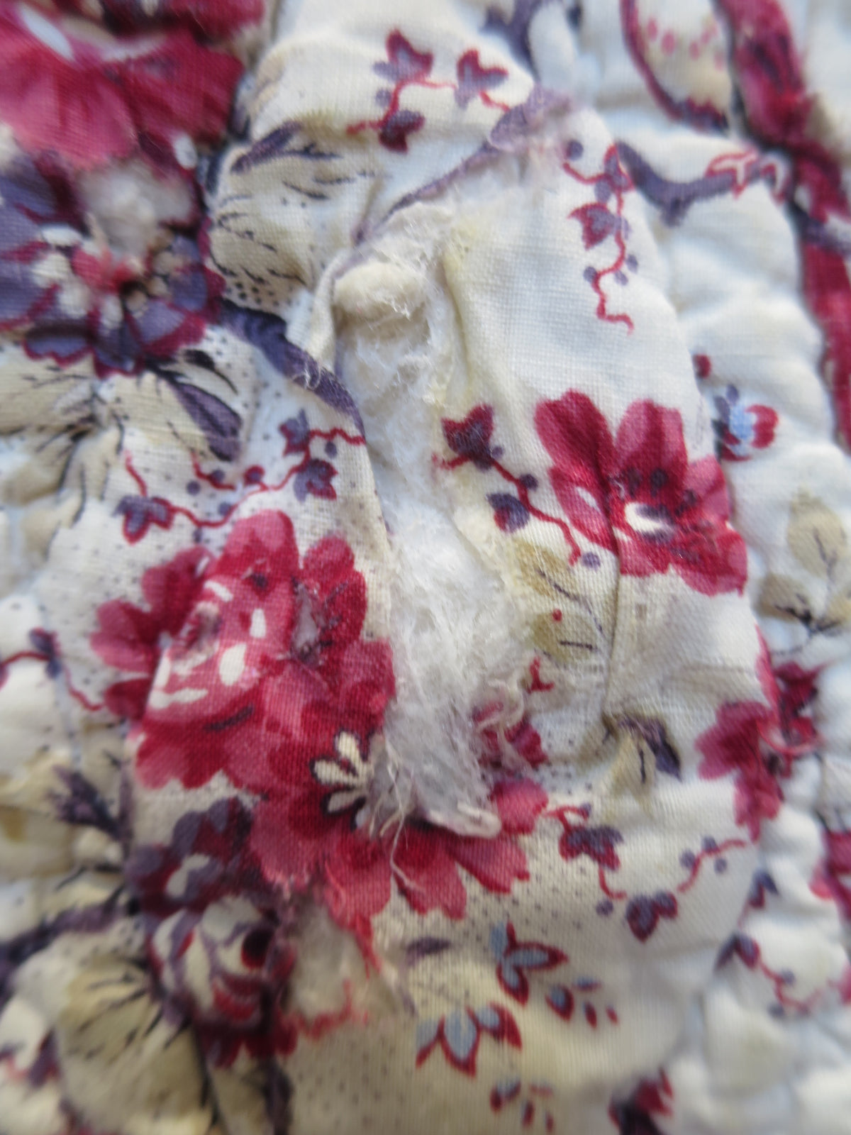 Area of wear on the bird-printed front of the French piqué quilt.