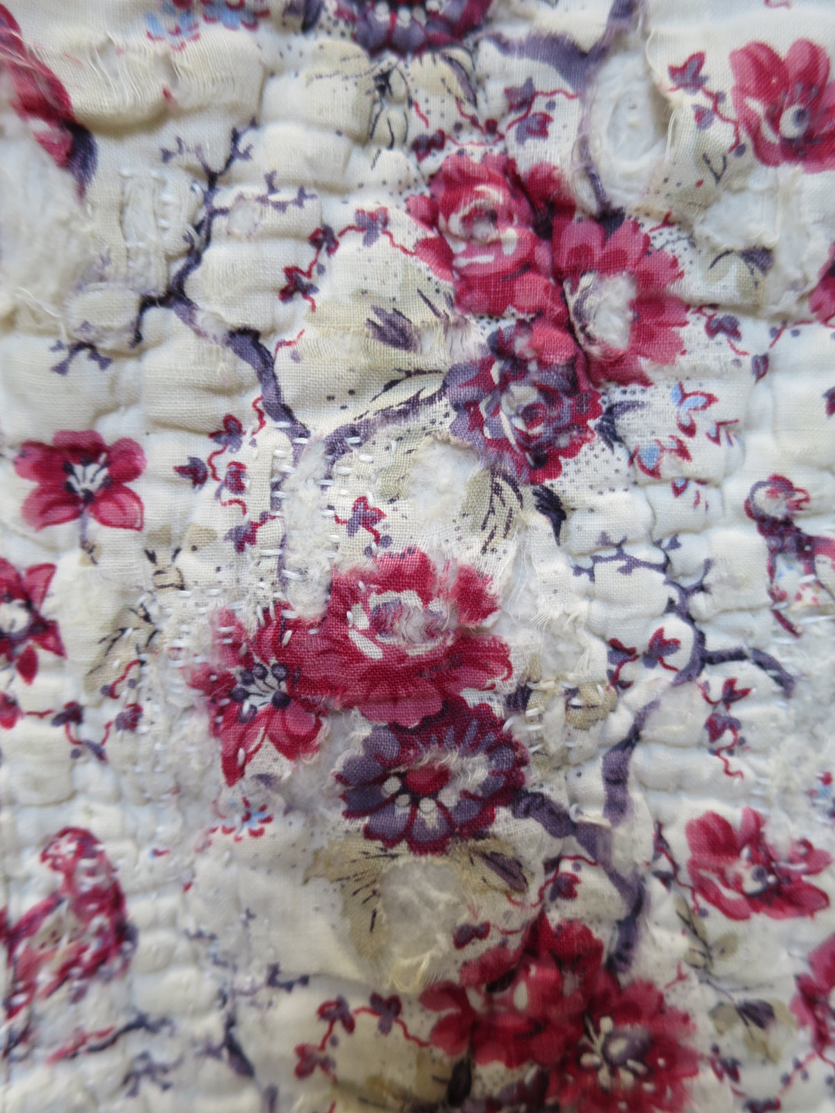 Area of wear on the bird-printed front of the French piqué quilt.