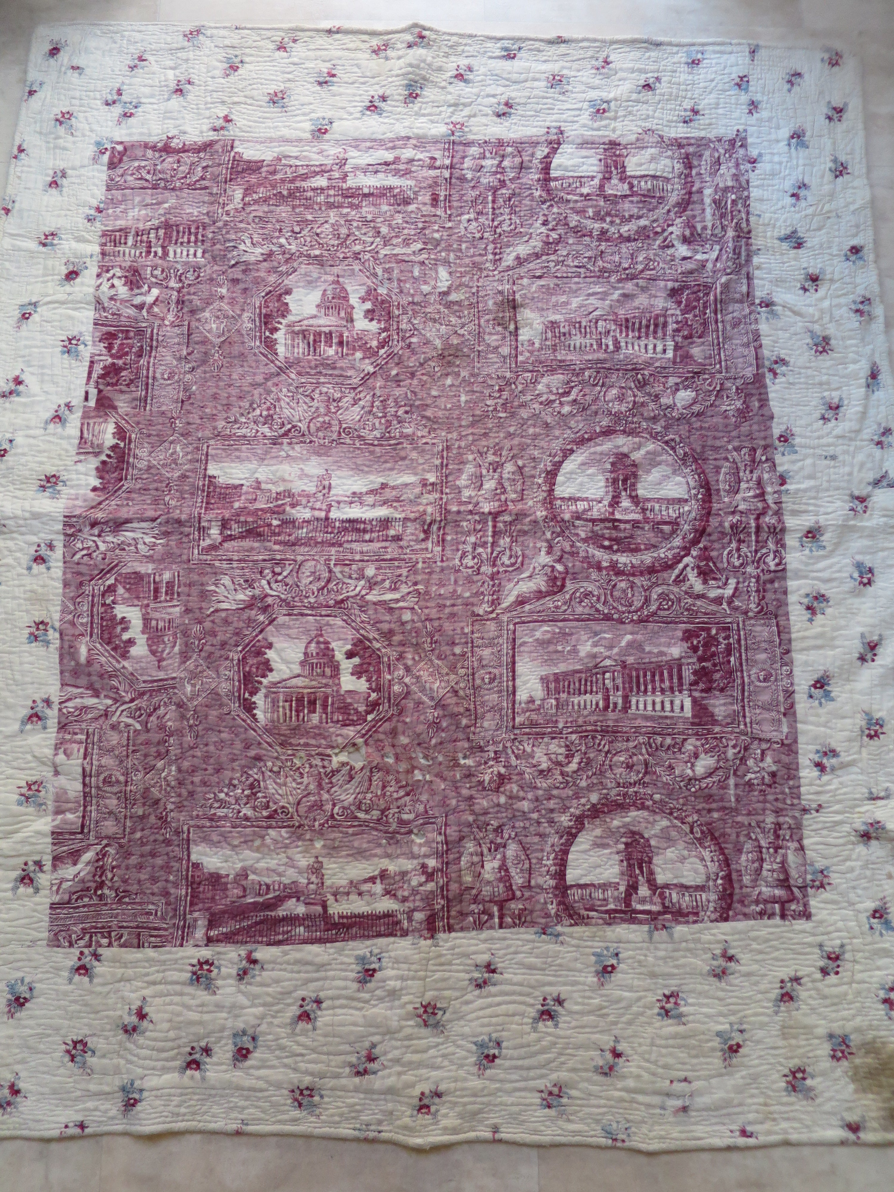 Full view of the French Provençal piqué quilt with its plum-coloured Les Monuments de Paris toile panel and floral border.
