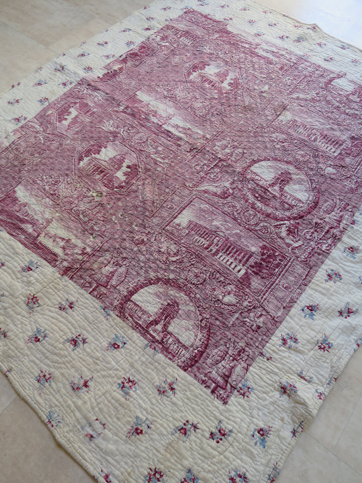 Full view of the French composite quilt, with the plum toile panel set within a cream border with floral block print.