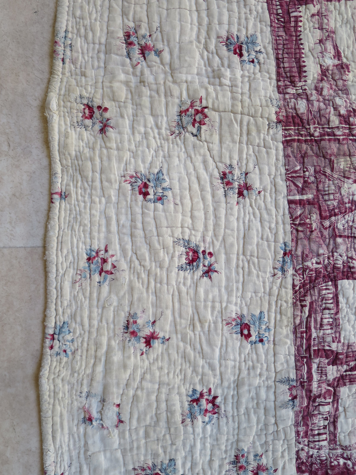 Detail of the block-printed border, with small red and blue floral sprigs on cream cotton.