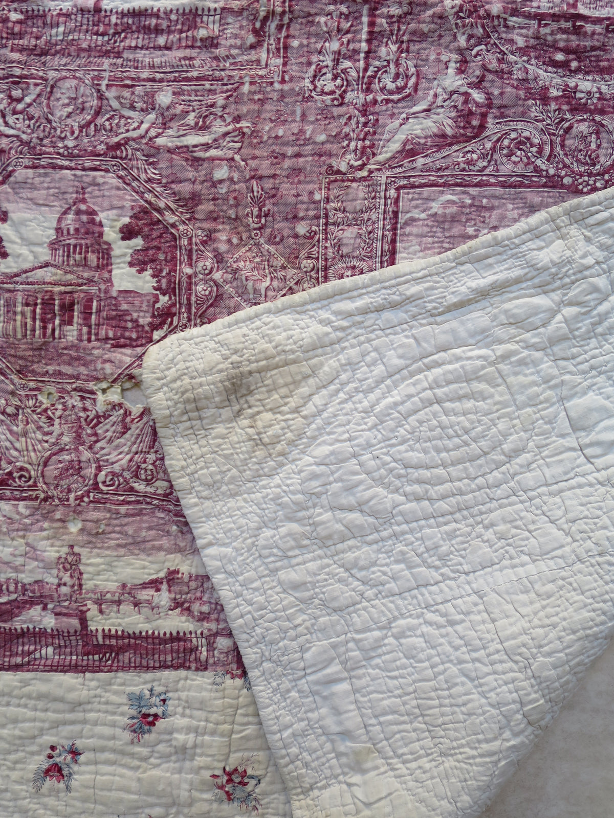 Front of the quilt folded back to show the plum toile panel and the hand-quilted reverse together.