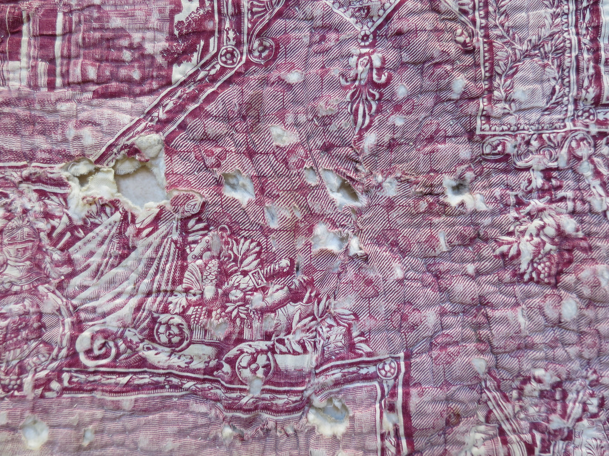 Close view of repaired splits and remaining holes in the stained toile panel on the quilt’s front.