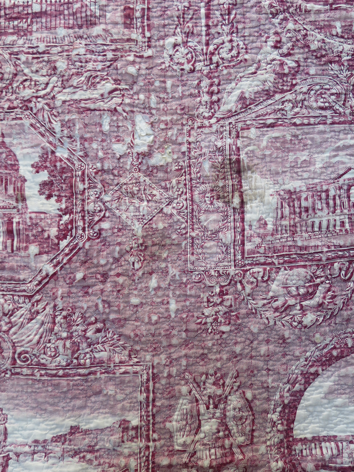 Detail of fabric wear and marks to the plum-printed front panel of the French quilt.