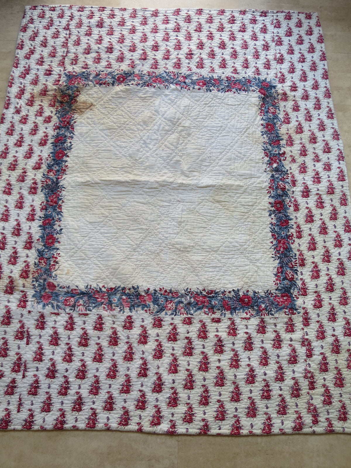 Early 19th-century French quilt, printed front with a central floral scarf and wide quilted border.