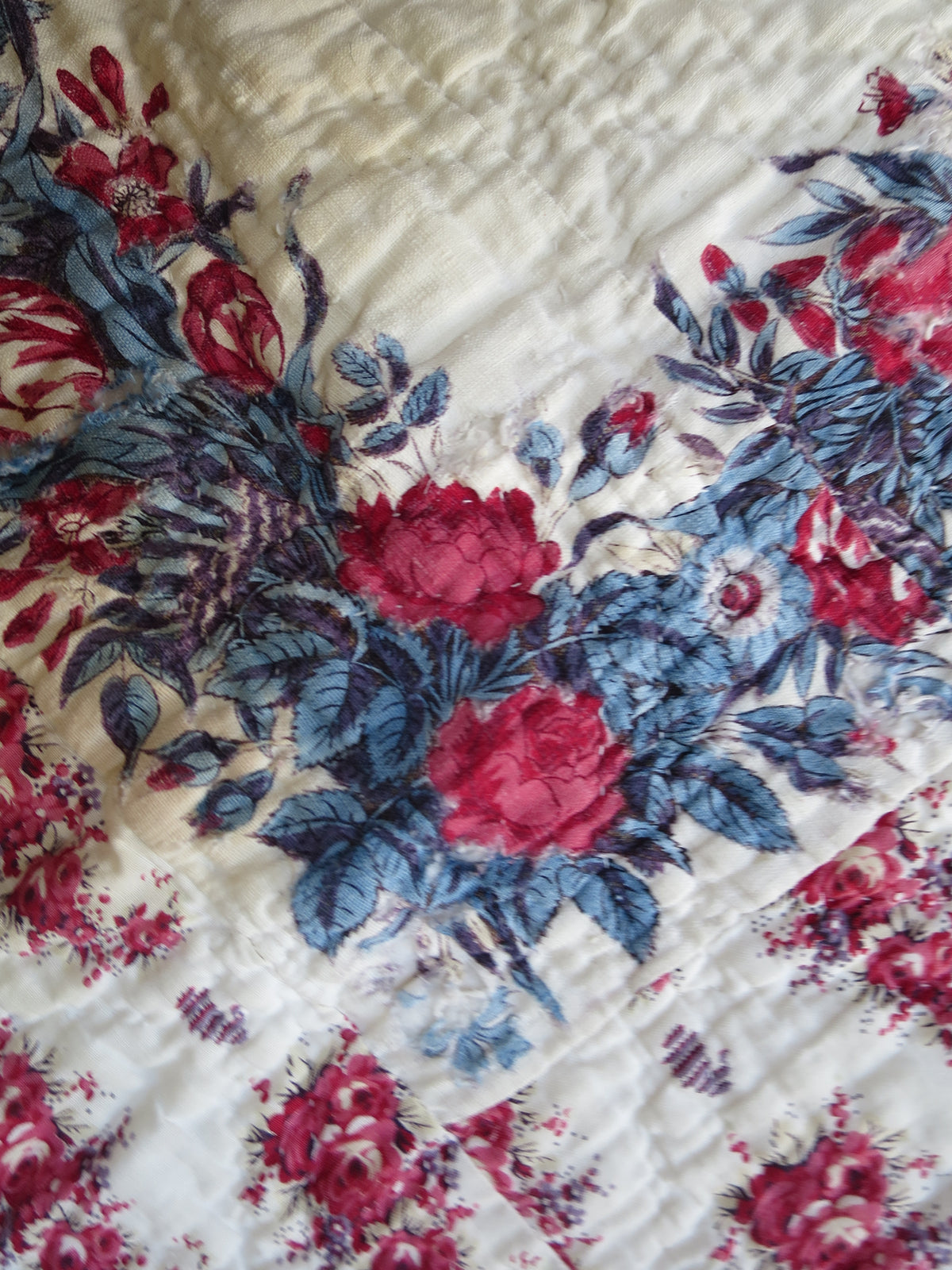Close view of a corner of the quilt’s printed scarf, with floral detail and surrounding quilting.