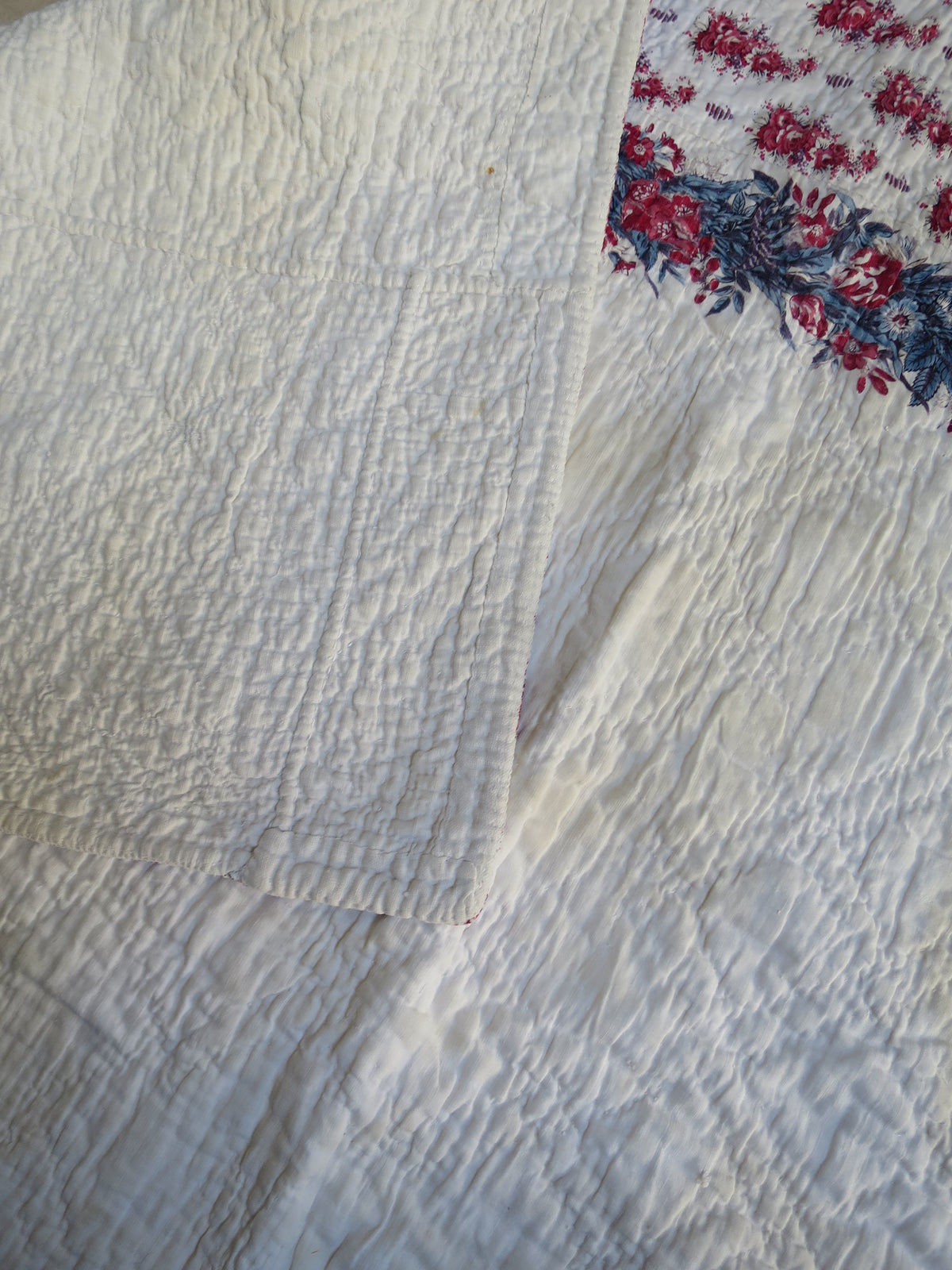 Printed front of the French quilt folded back to reveal its white quilted reverse.