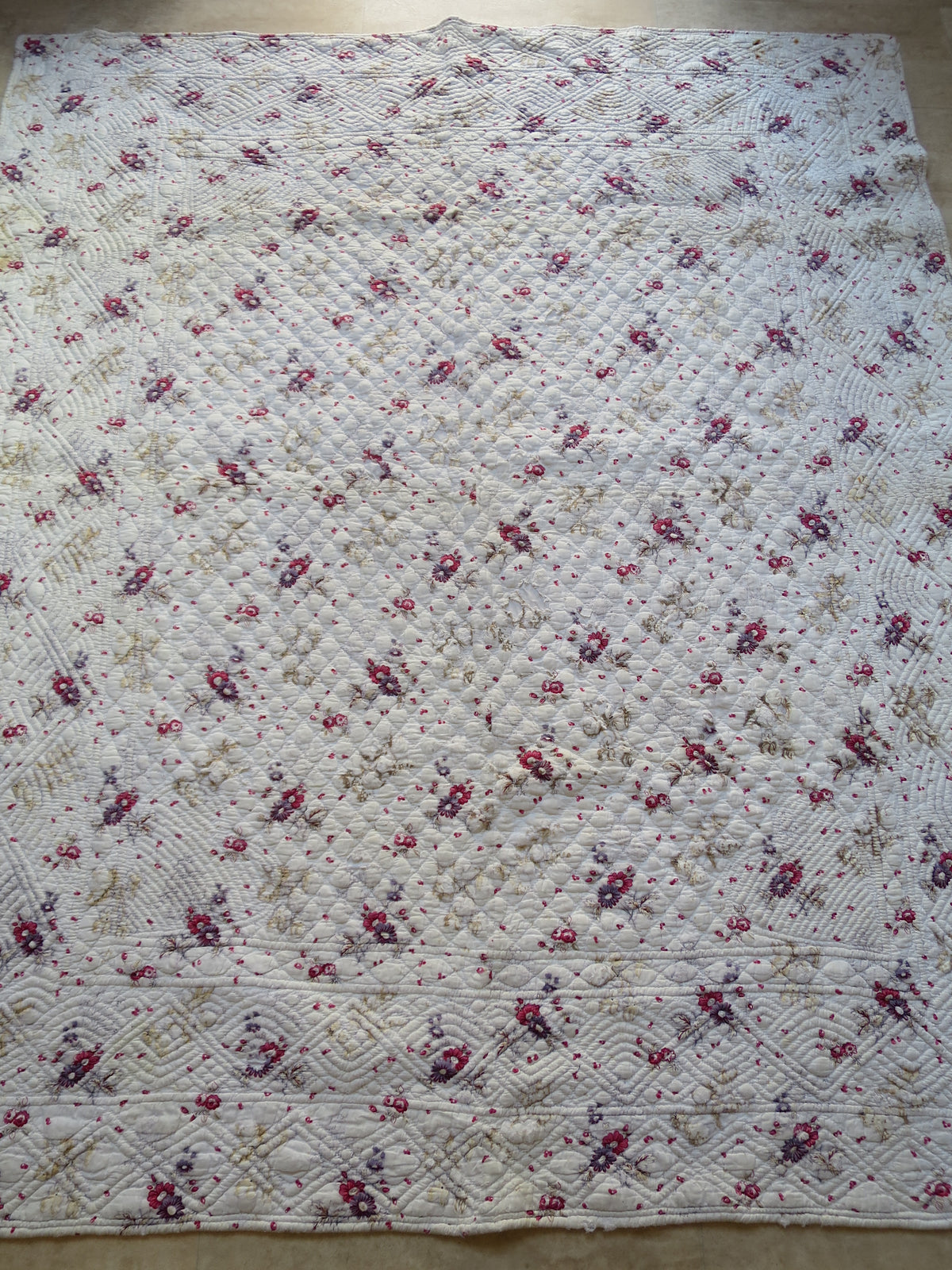 Full front view of the French piqué quilt, with block-printed floral sprigs and visible hand quilting.
