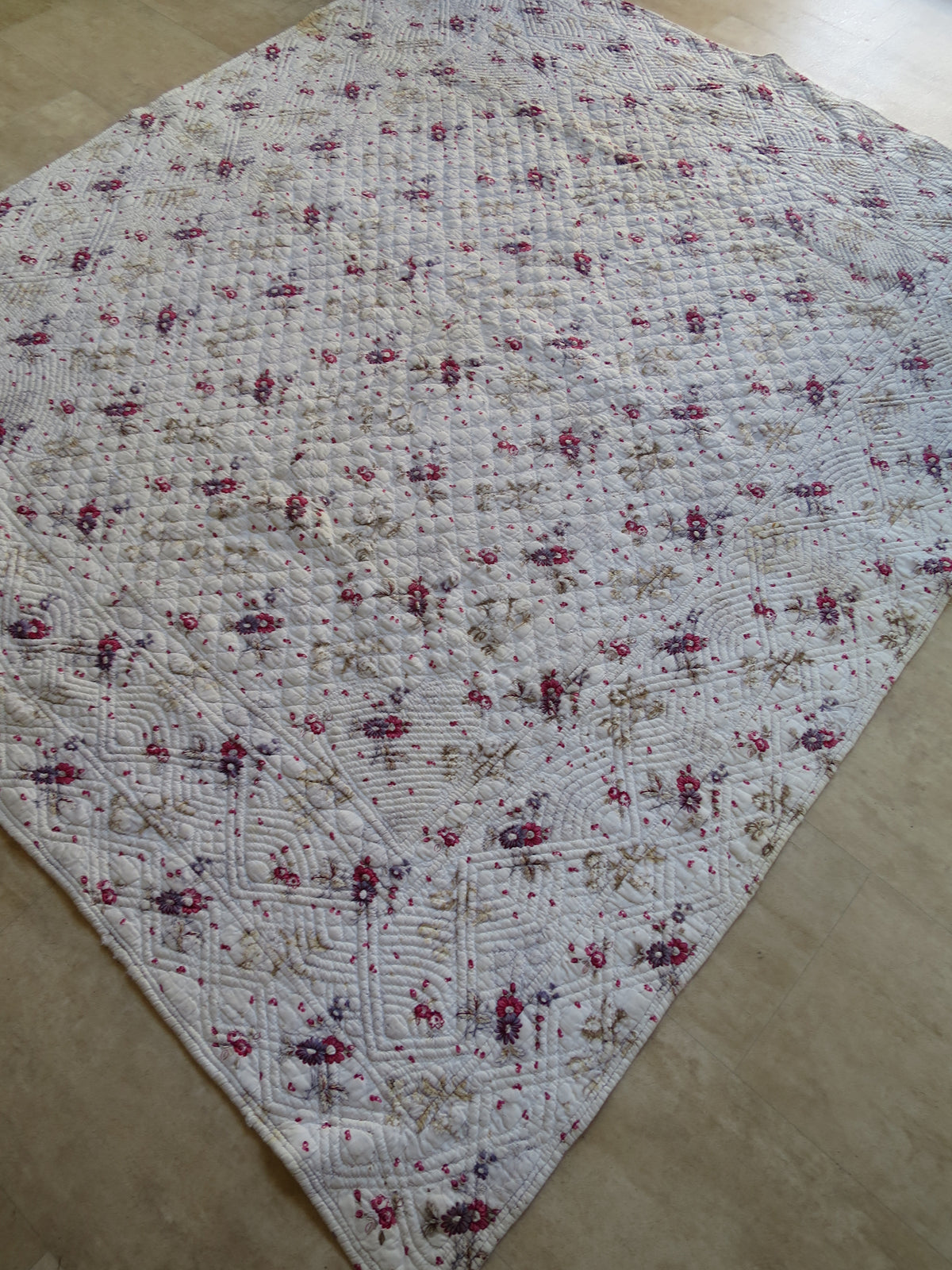 The whole printed face of the French quilt, showing its floral pattern and quilted layout.