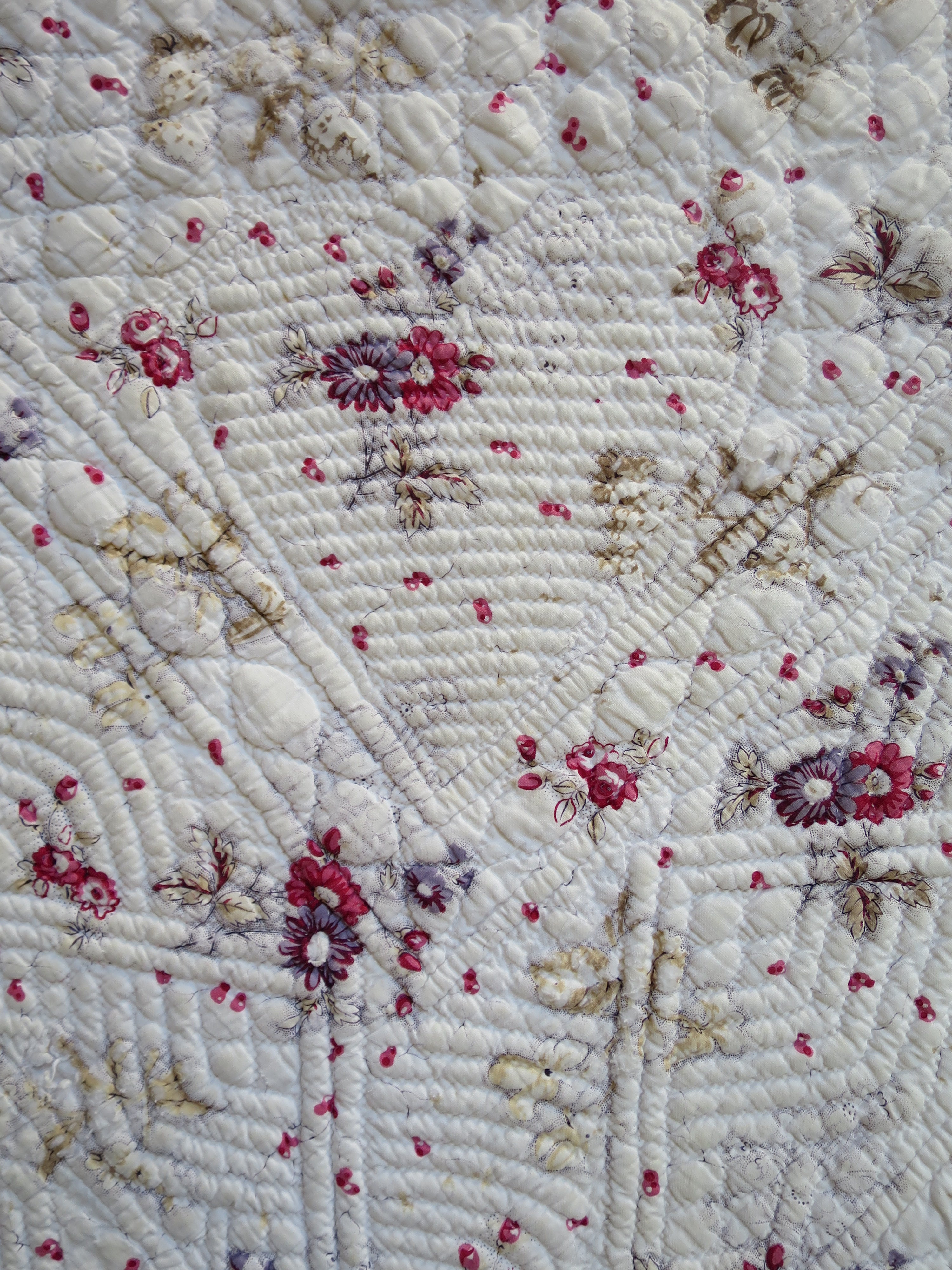 Corner of the French piqué quilt’s printed face, showing the raised, quilted heart motif.