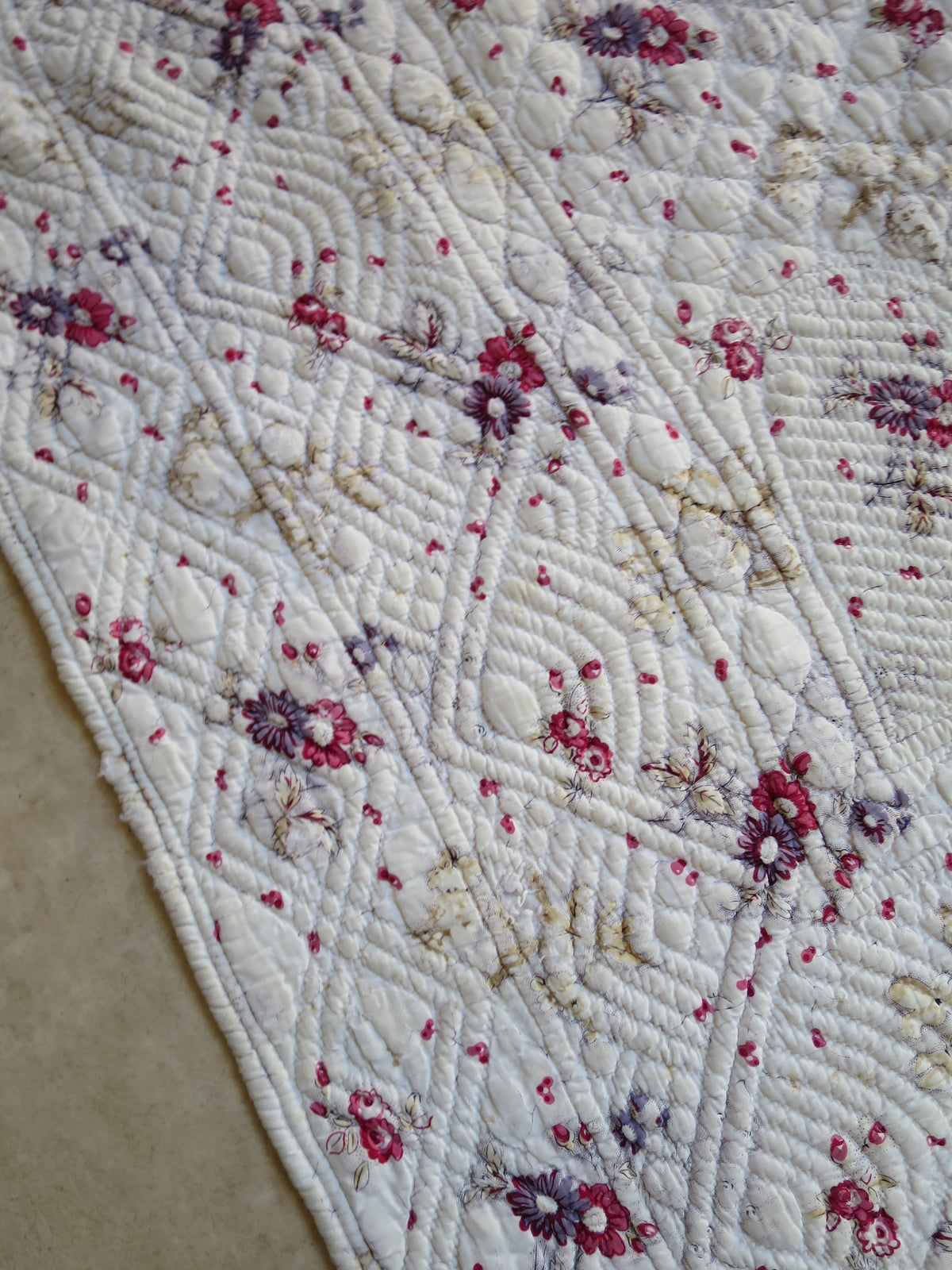 Detail of the hand-quilted border on the floral-printed front of the French piqué quilt.