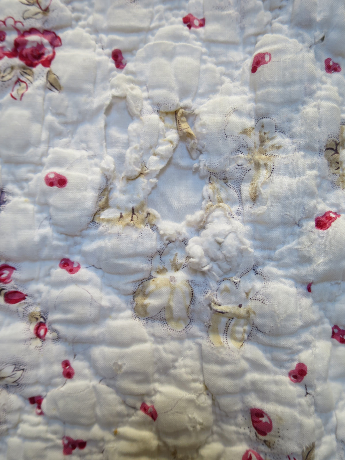 Area of wear on the floral-printed front of the French piqué quilt
