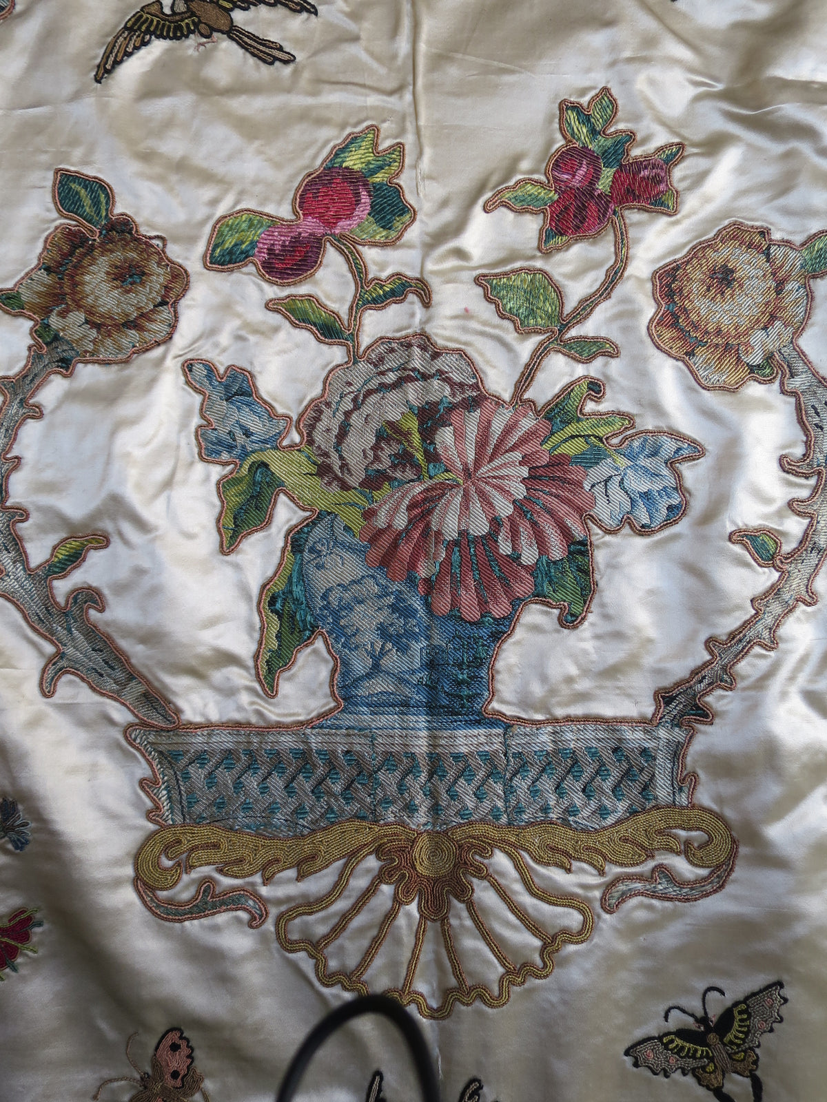 Appliqué motif cut from patterned lampas silk and mounted on the coverlet’s satin ground.