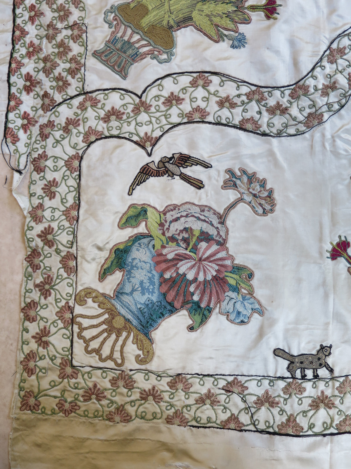 Corner of the silk coverlet, showing its edge and applied design.