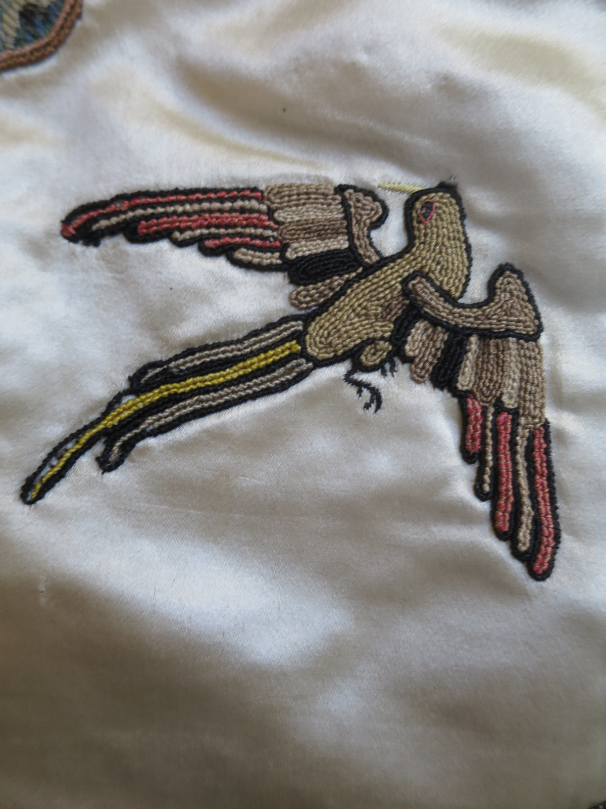 Close detail of a second slip-style silk appliqué motif on the coverlet.