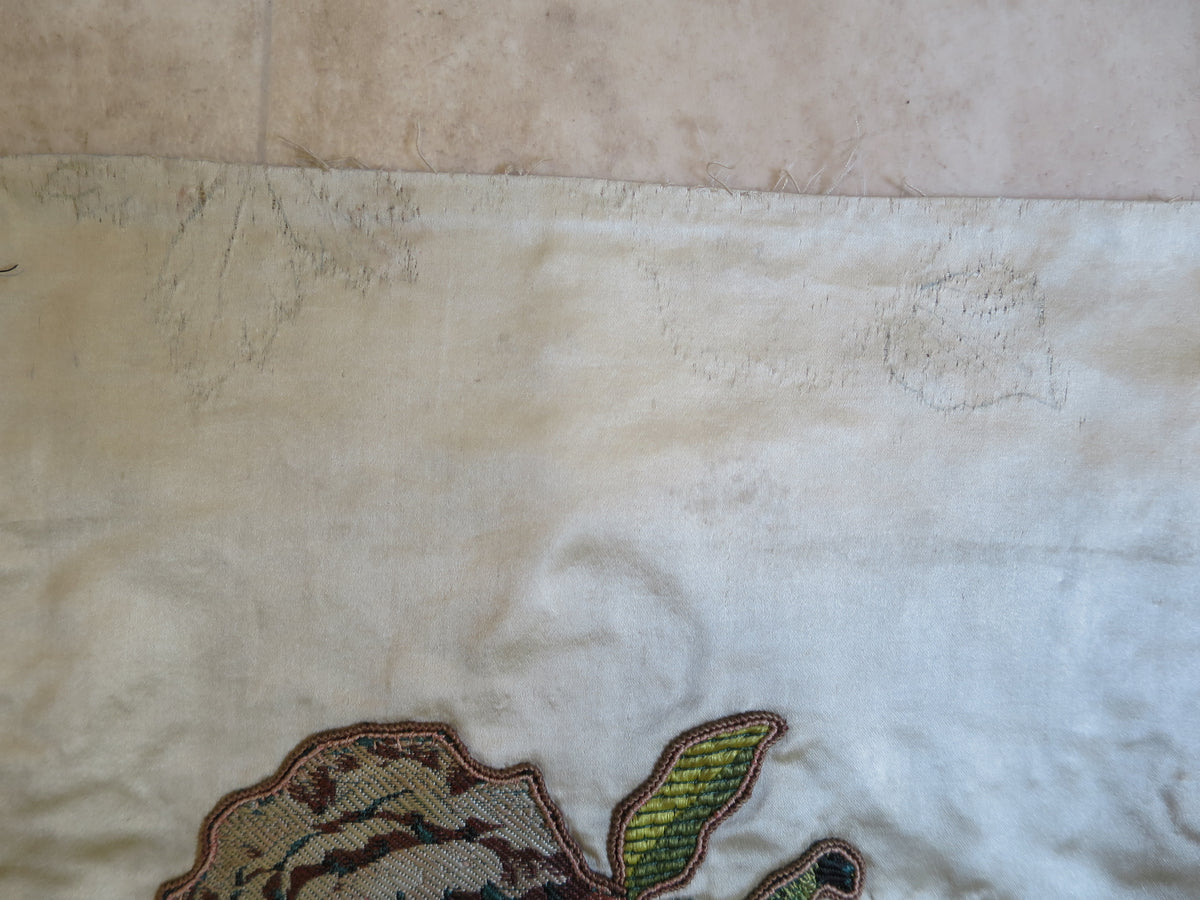 Detail of the coverlet’s top edge, with an original embroidery design visible beneath unpicked stitching.
