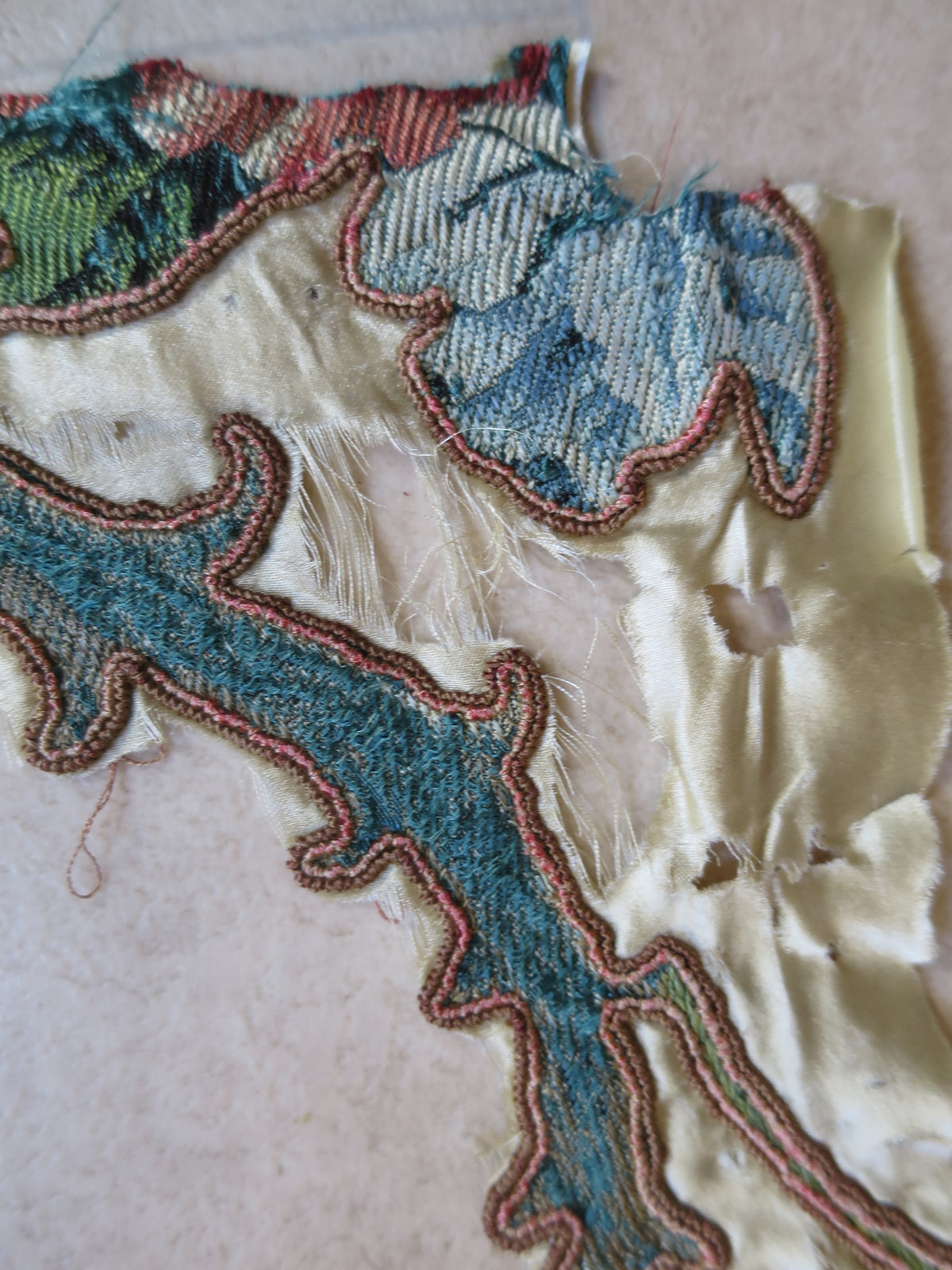 Close-up of wear on a detached lampas silk appliqué fragment.